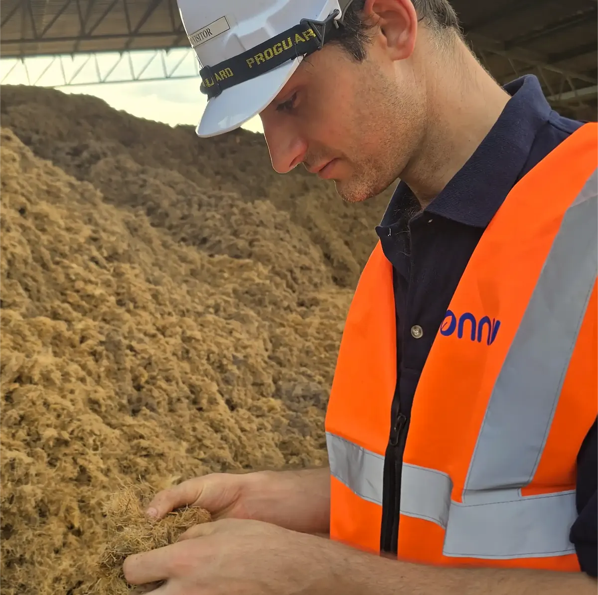 Onnu engineer in hi-vis checking biomass feedstock by hand