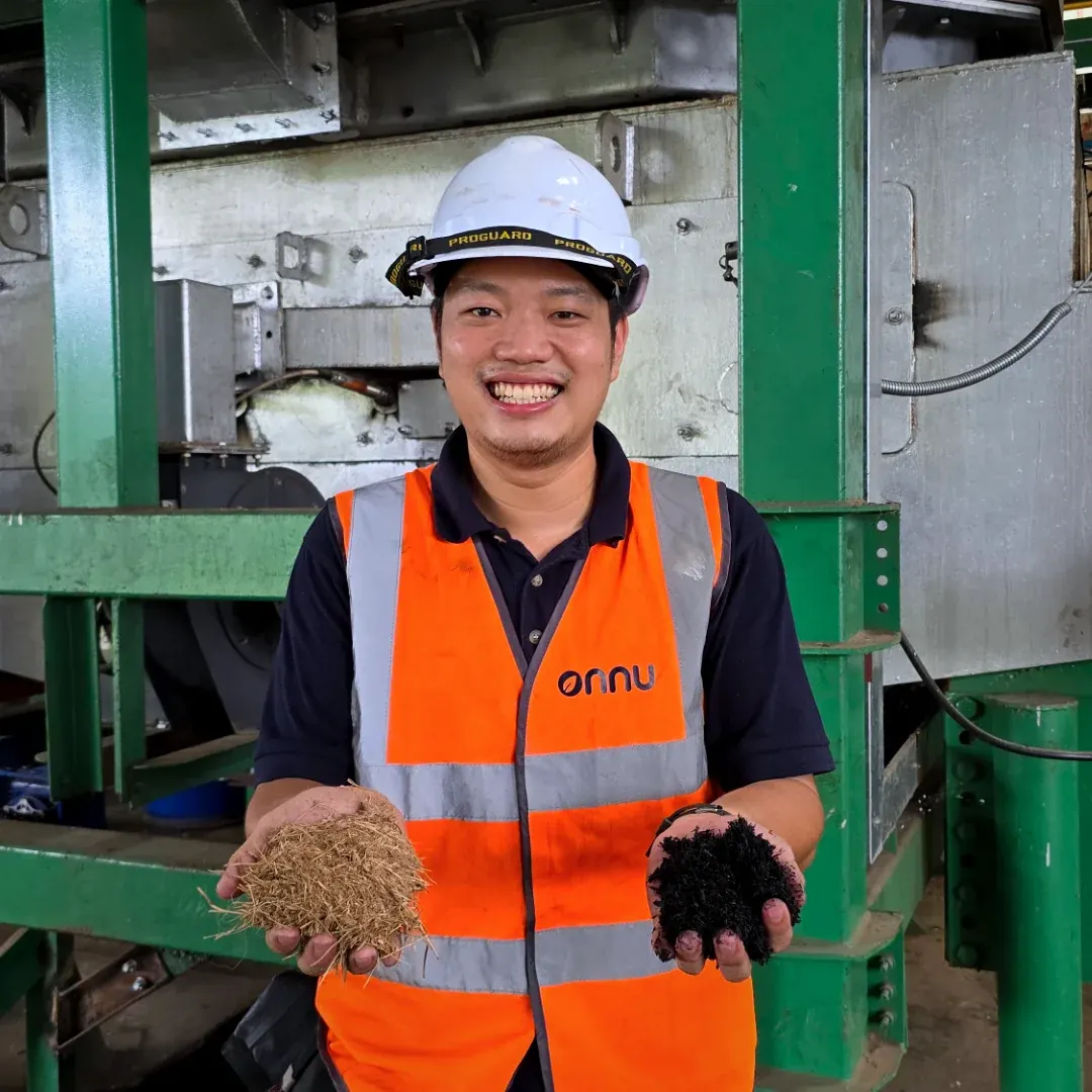 Onnu engineer holding raw feedstock in one hand and finished biochar in the other