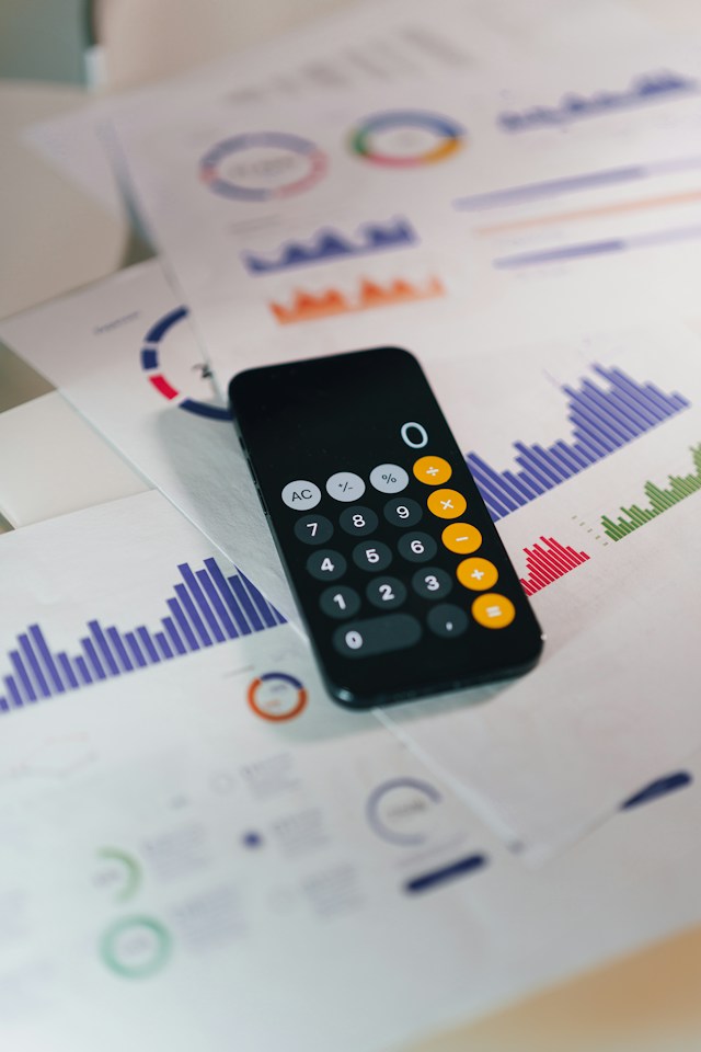 Calculator resting on printed charts and financial reports